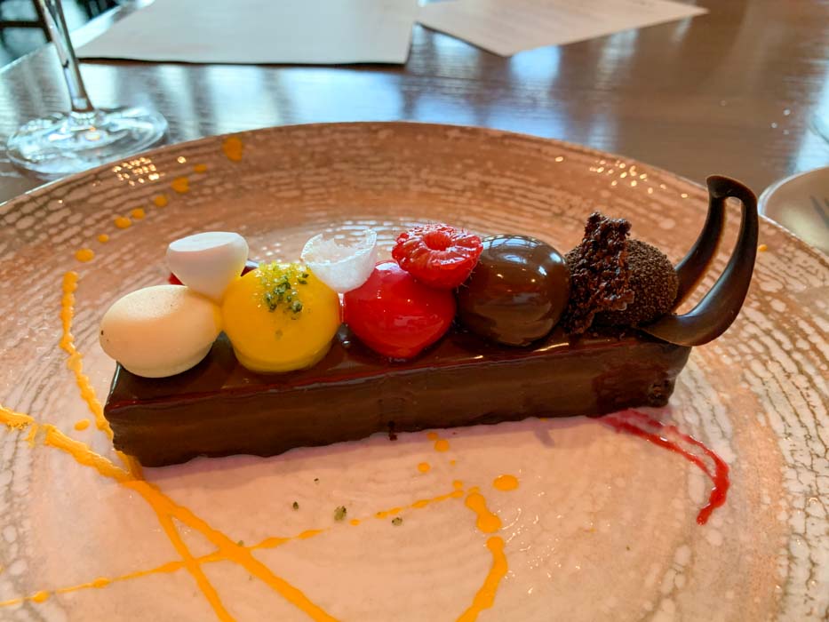 A chocolate dessert with colorful truffles on top, on a white plate