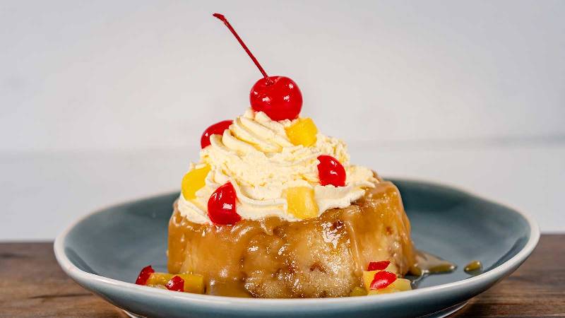 A pineapple bread pudding with whipped cream and a cherry on top
