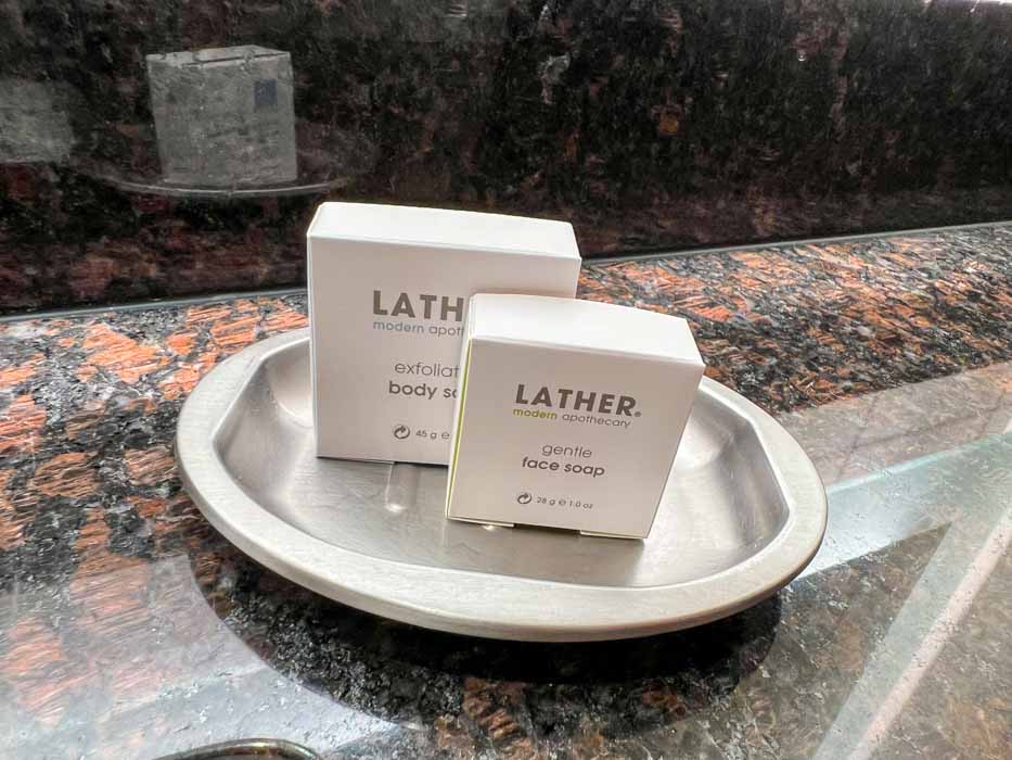 Lather brand toiletries sit on a silver tray on the bathroom counter