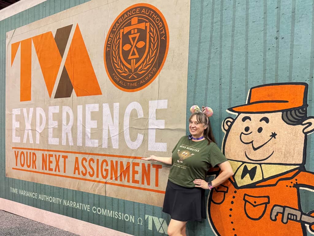 Woman in a green shirt stands in front of a large mural that reads "TVA Experience"
